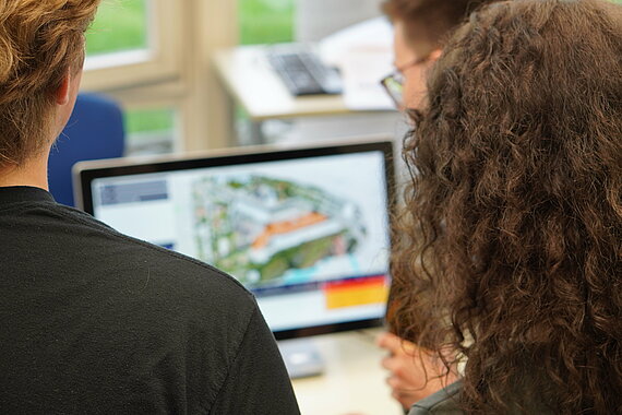Blick über die Schulter von Studierenden (m/w) auf eine Projektsimulation (auf einem Desktop)
